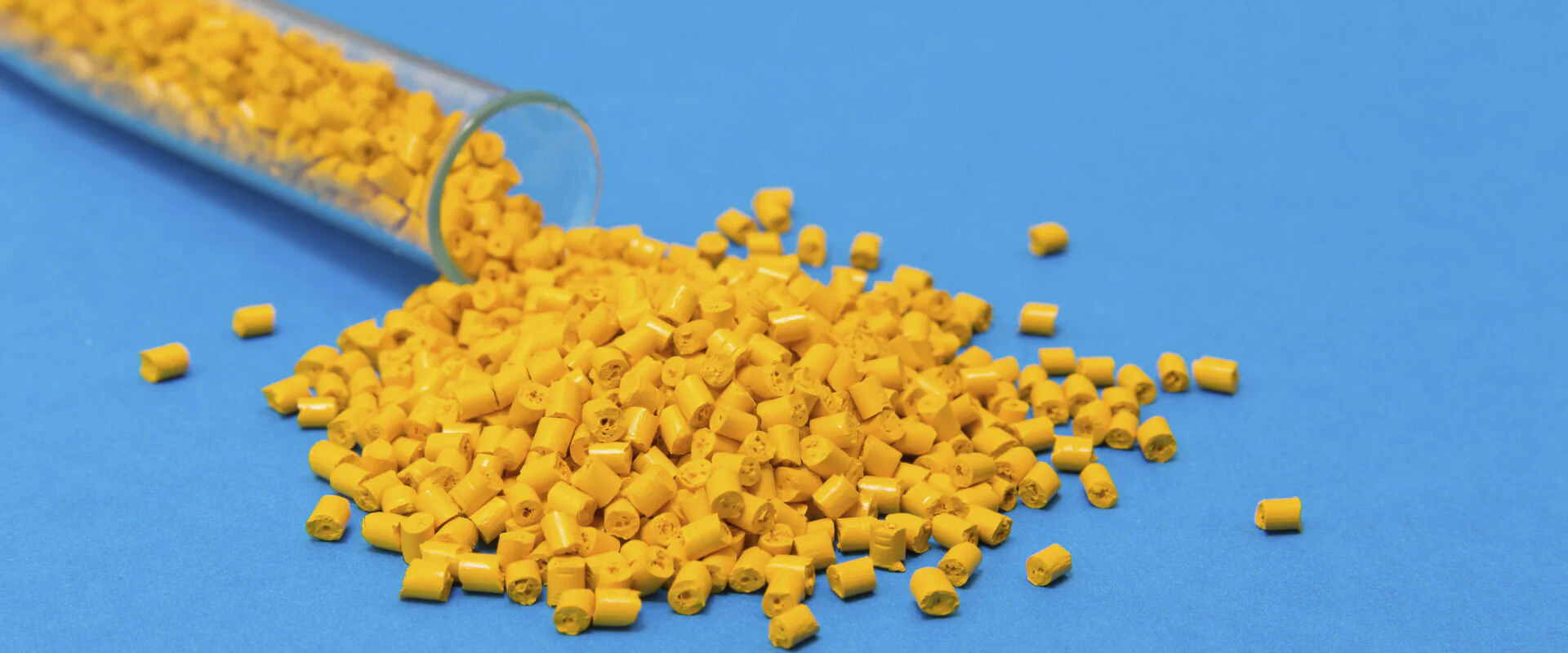 Kunststoff Bildbeschreibung / description: Gelbe Plastikpalletts rollen aus einem Reagenzglas auf blauem Untergrund